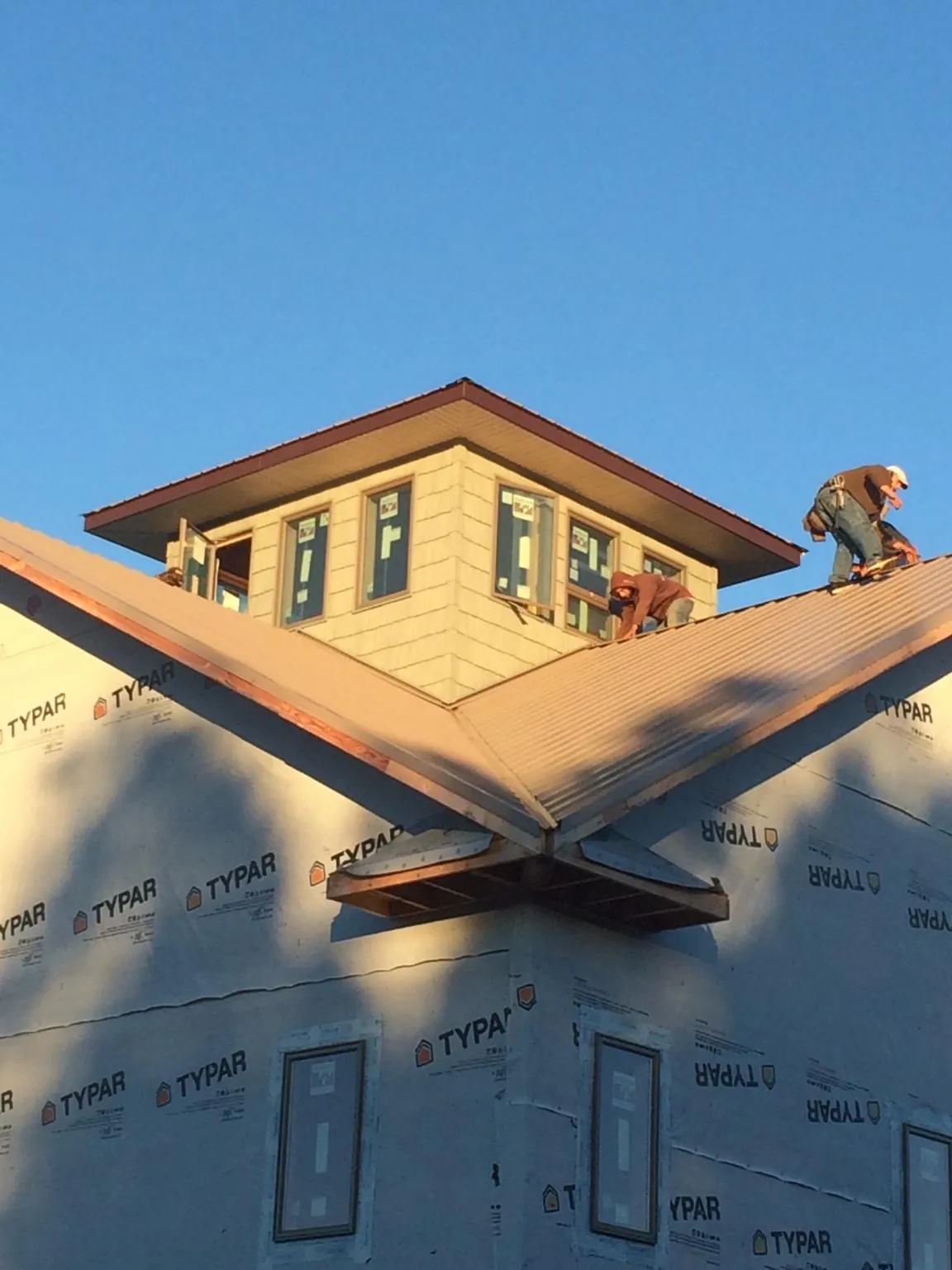 Roofers working around a rooftop cupola on a new metal roof at sunset — Roof Waterproofing in Arcadia by Roofing Brothers